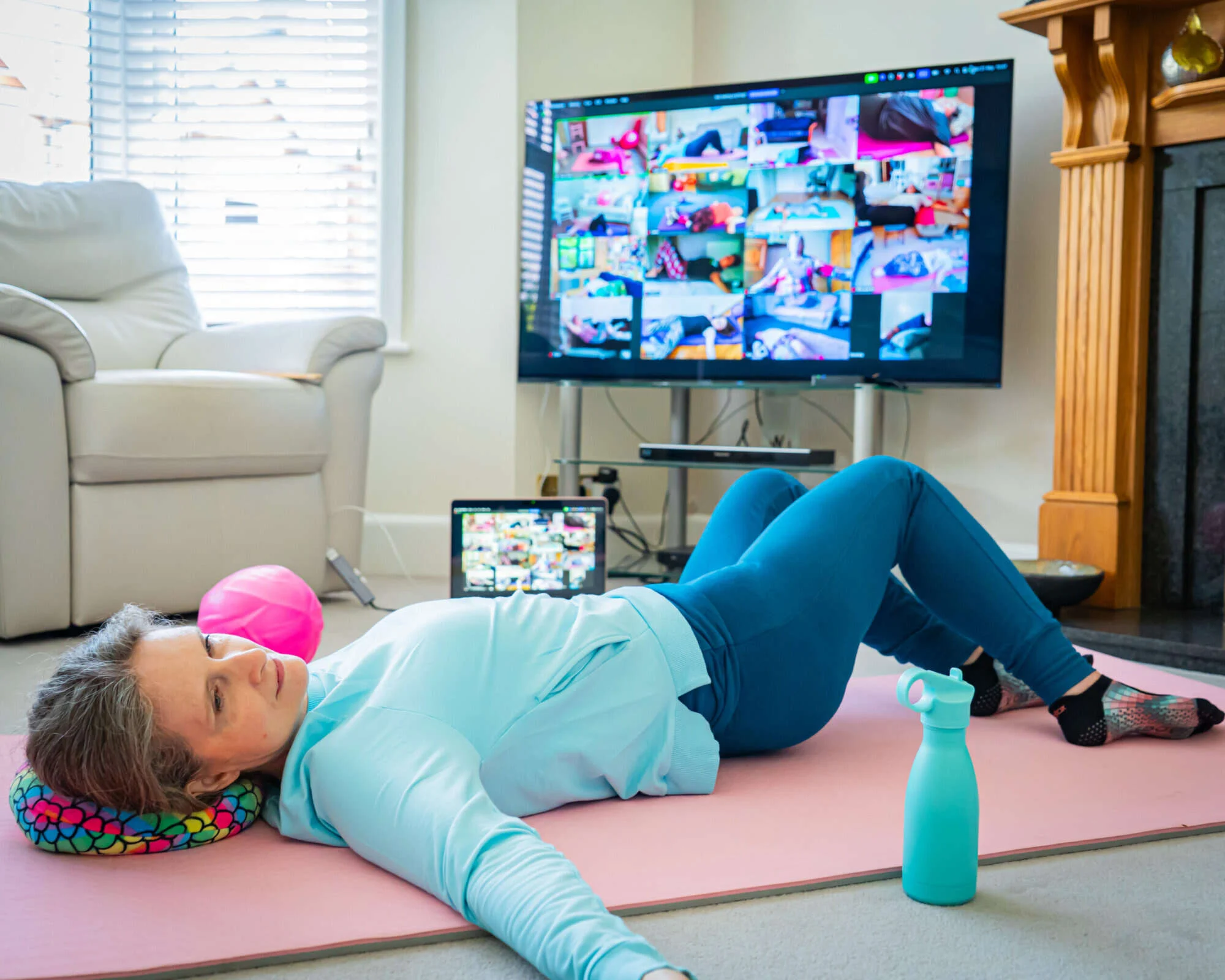 Mobilates member exercising on a mat while following an online class