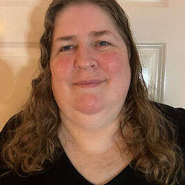 Headshot of a smiling Mobilates member with curly brown hair
