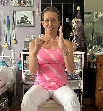 Suzanne, our member and teacher, demonstrating a move in class, sitting with one hand in a fist.