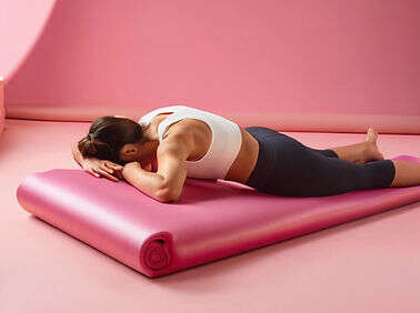 Person lying face-down on a pink exercise mat, resting