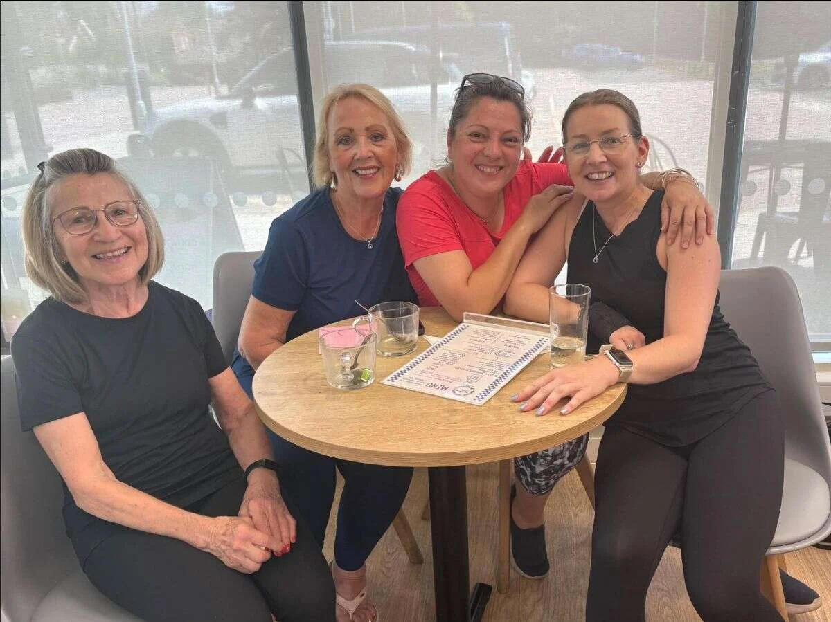 Four Mobilates members smiling together around a cafe table at Paddock Wood