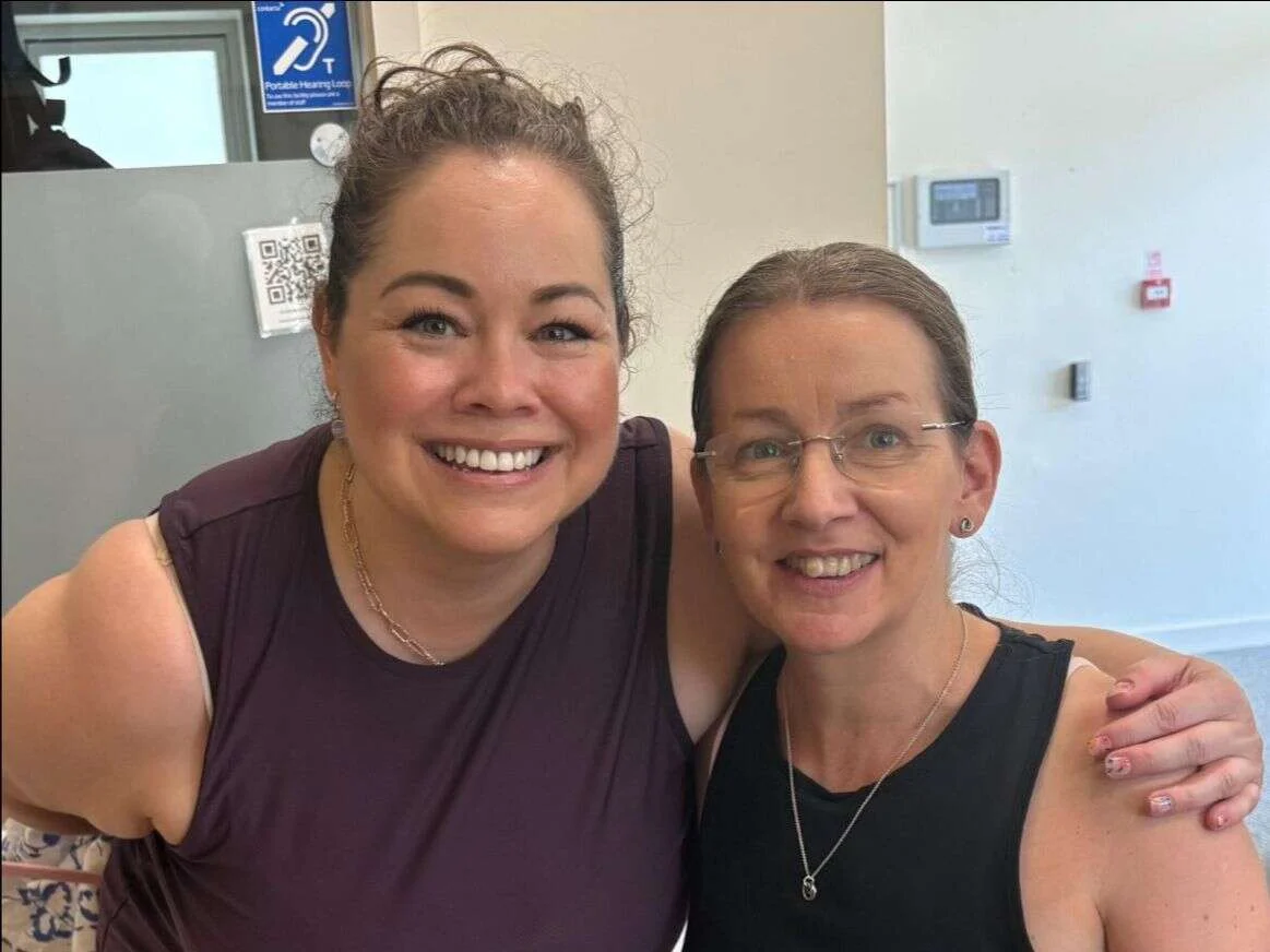 Suzanne and a fellow Mobilates instructor smiling arm in arm after Suzanne's Pilates assessment