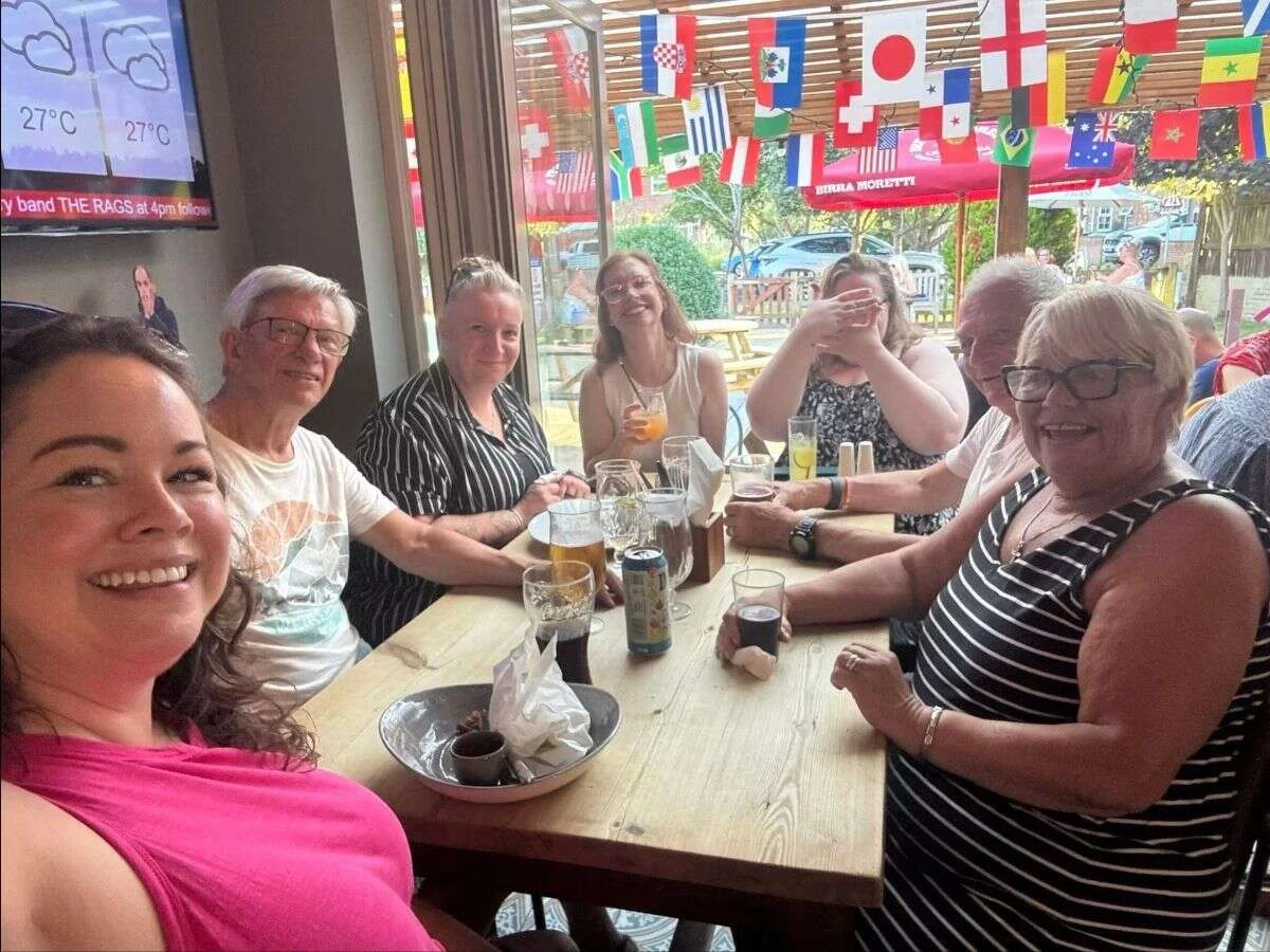 Suzanne and Mobilates members and family celebrating together at a pub with flag decorations