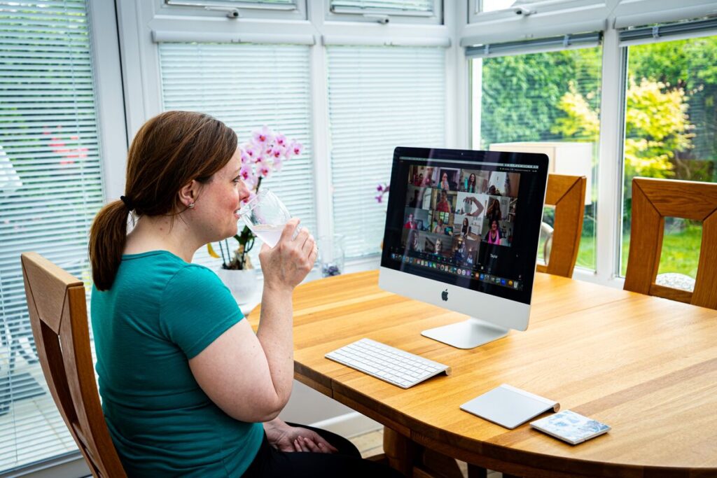 A woman sits at her dining table, working at a computer.