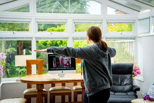 A Mobilates member enjoying a virtual class from the comfort of her conservatory